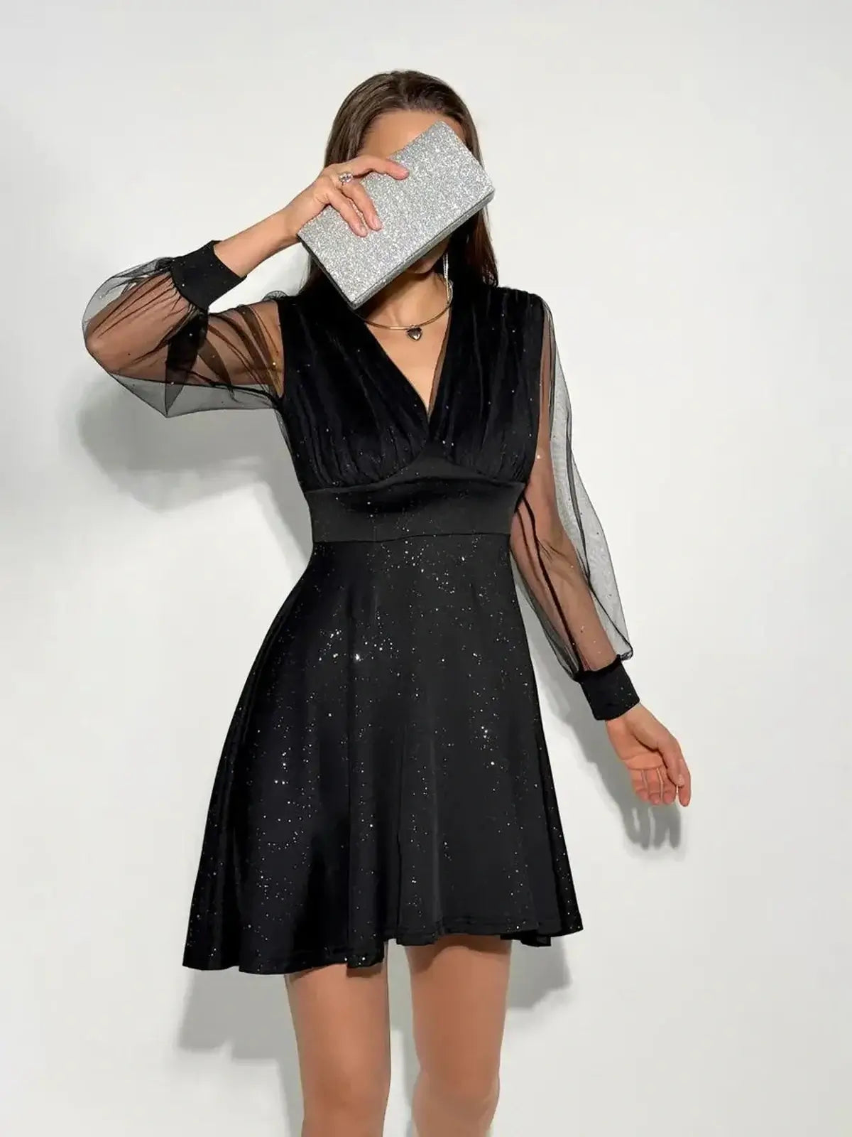 Black mini dress with plunging V-neckline and sheer long sleeves, perfect for parties and special occasions.