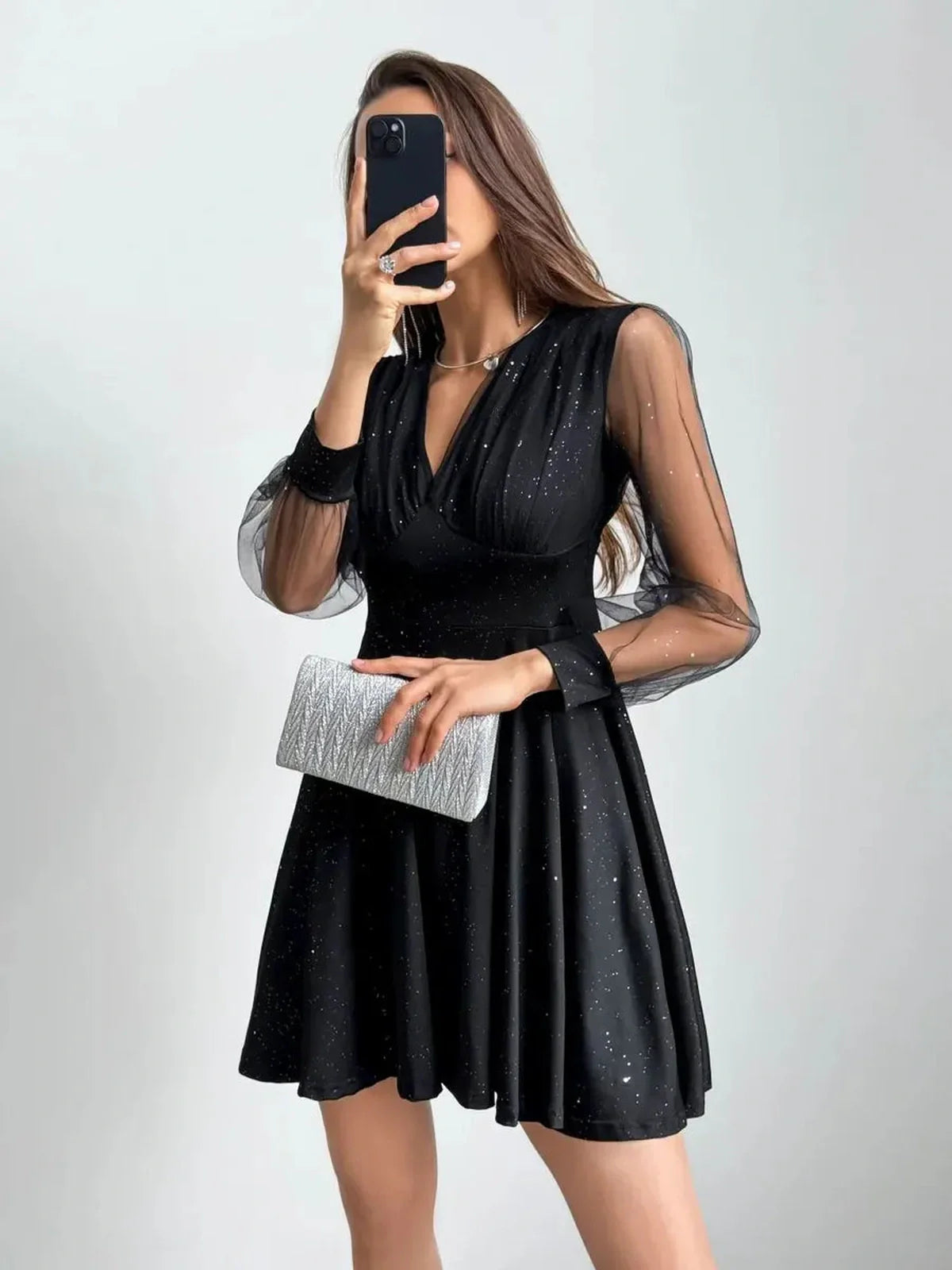 Model wearing a stunning black mini dress with long sheer sleeves, perfect for evening events or special occasions.