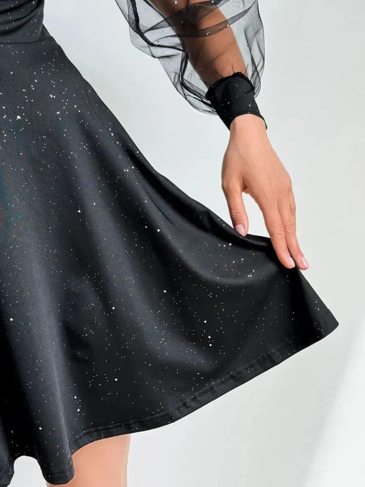 Black mini dress with sheer long sleeves and shimmering fabric, perfect for parties and formal events.