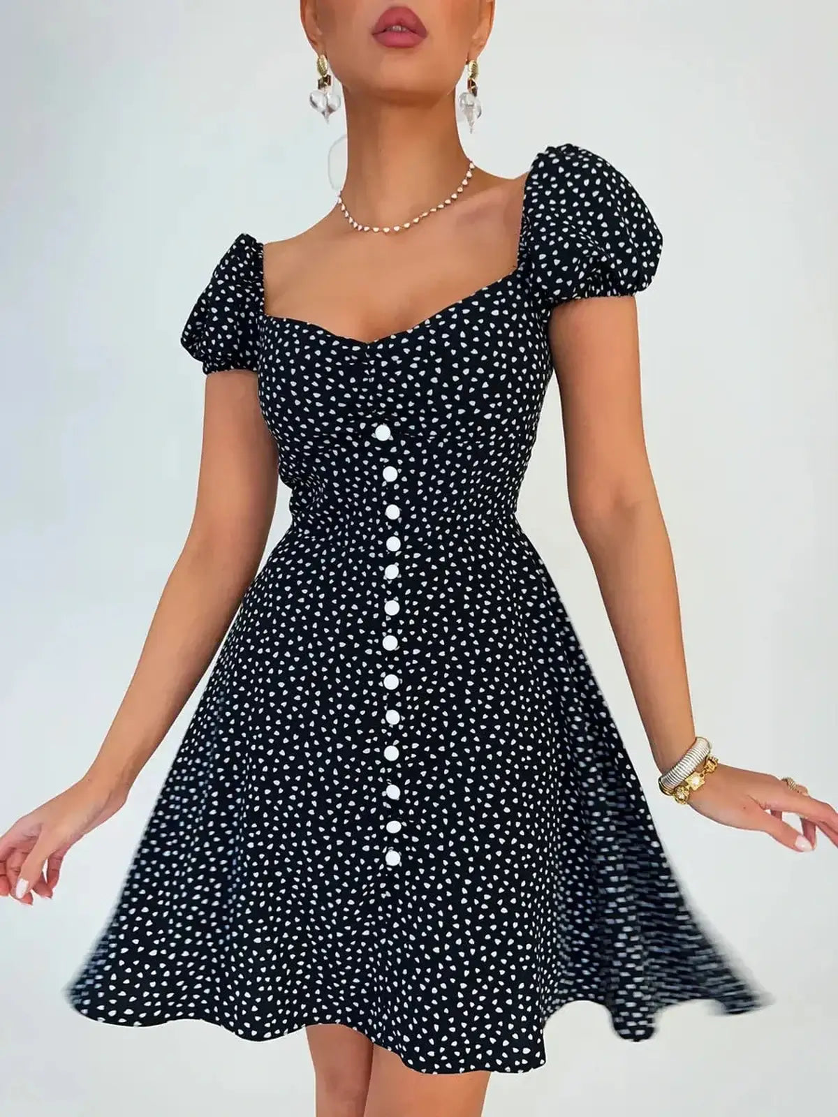 Noir Chic Mini Dress in black with white dots, featuring a sweetheart neckline and puff sleeves, perfect for summer occasions.