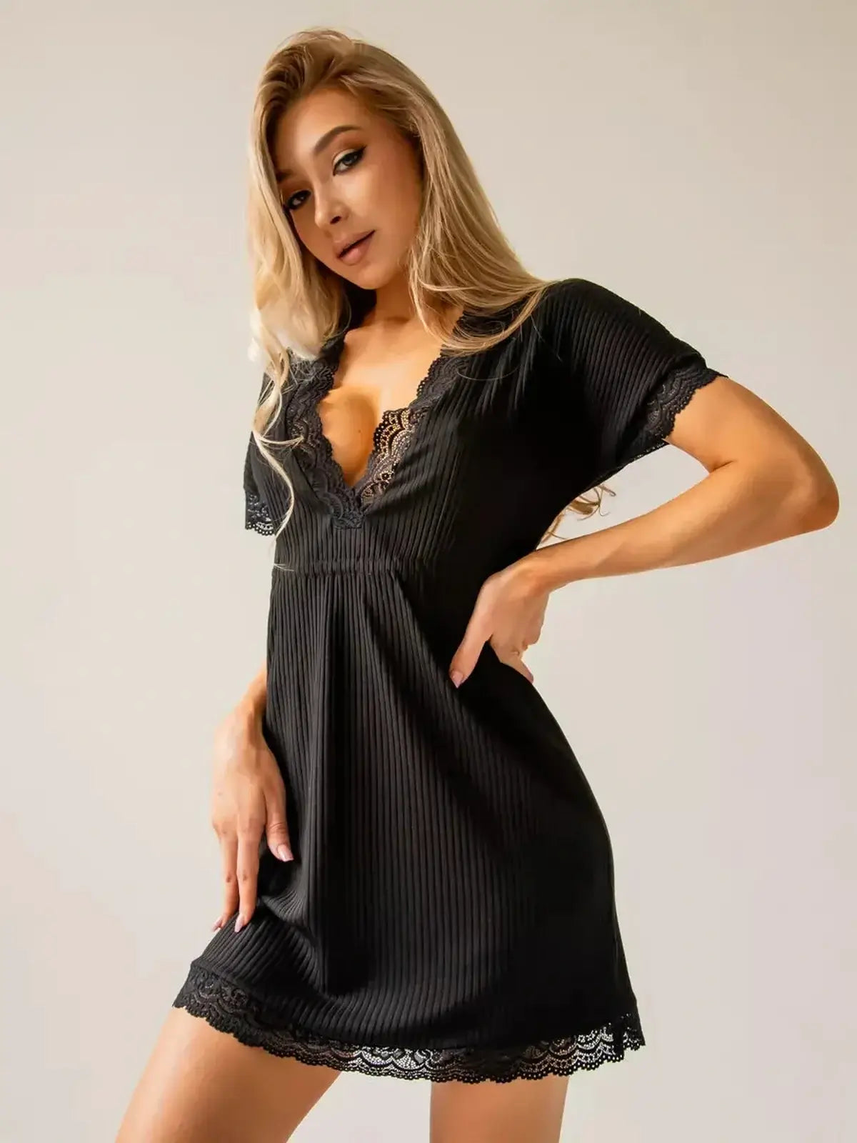 Stylish woman modeling a black mini dress with ribbed texture and lace trim, perfect for summer occasions.