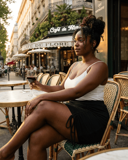 Woman enjoying a drink in Paris wearing a Noir Mini Skirt from Slimona, highlighting its high-waisted, bodycon silhouette.
