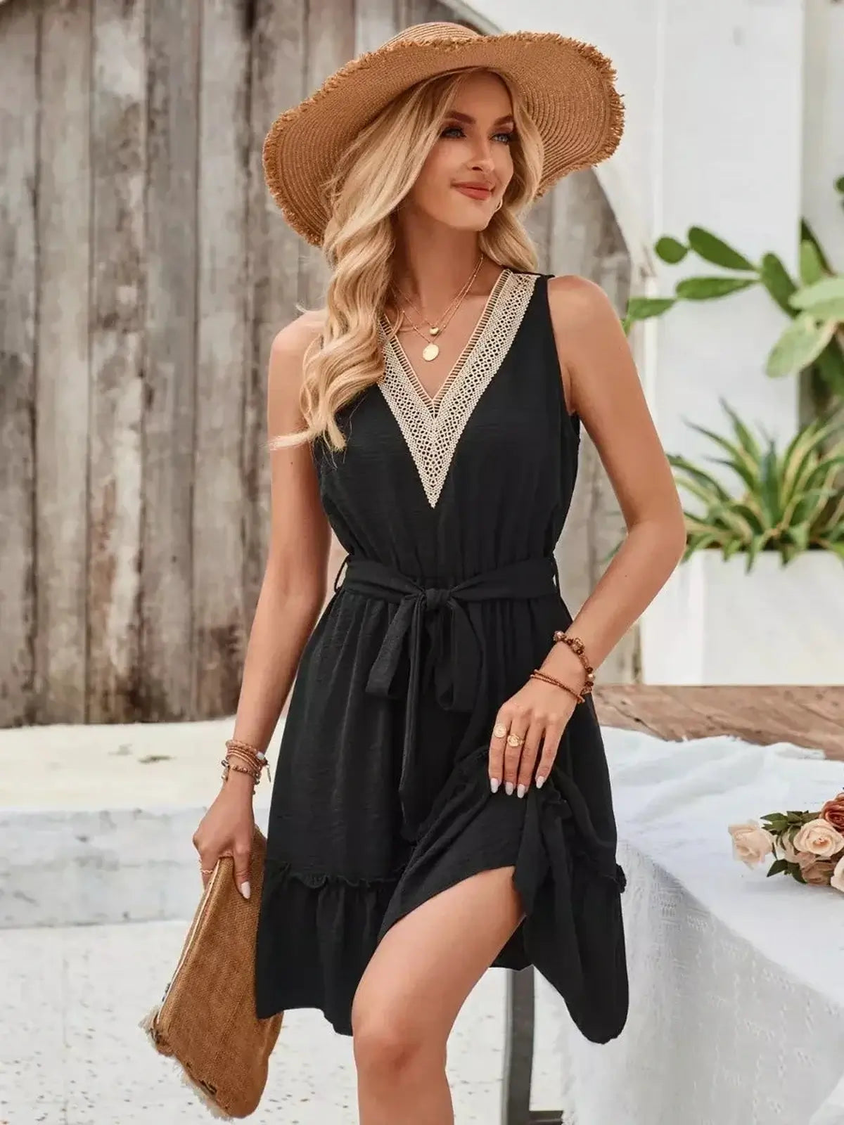 Stylish woman in a black mini dress with crochet detail and a tie-waist, perfect for summer and wedding guest occasions.