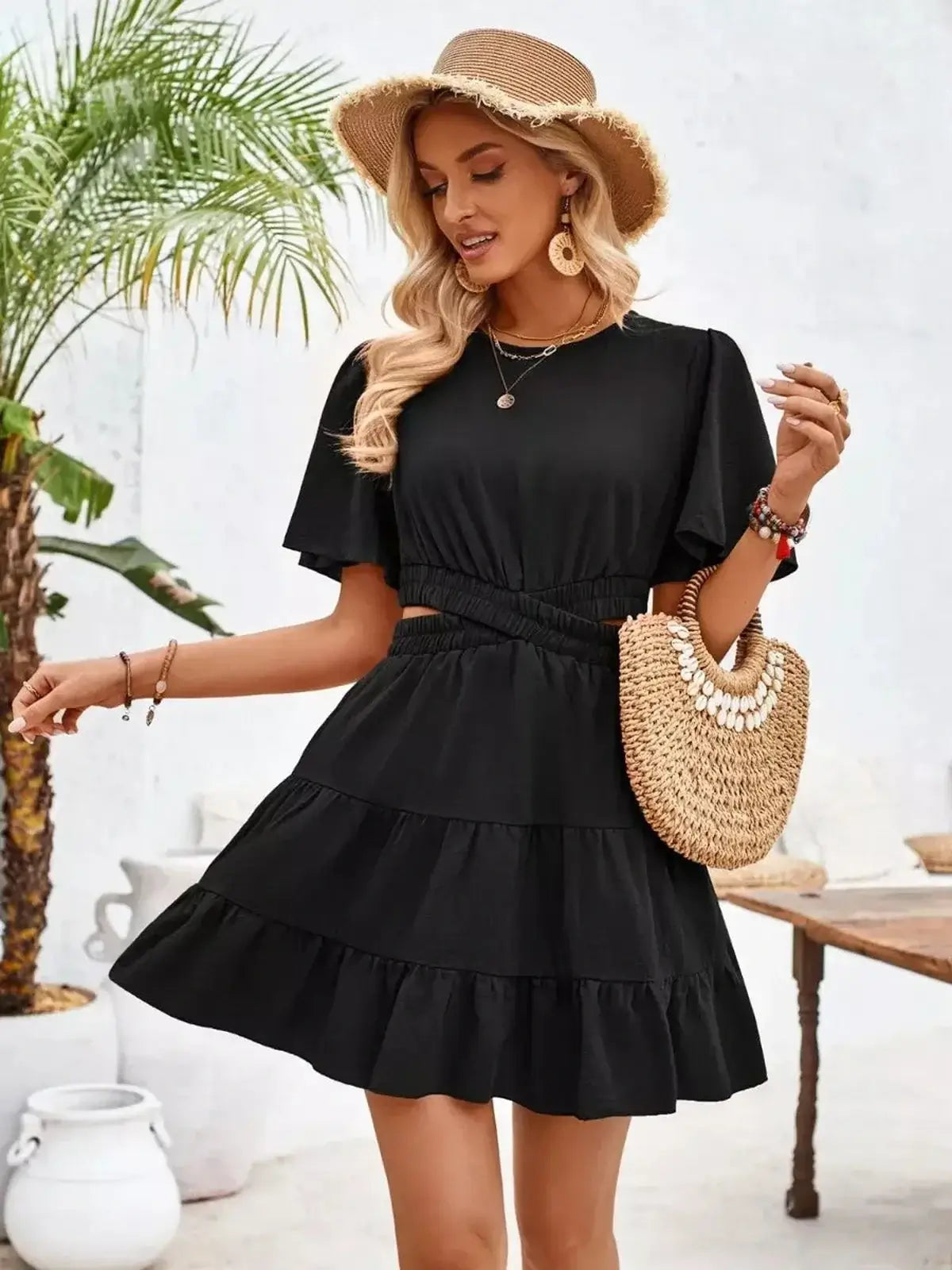 Stylish woman wearing a black mini dress with tiered skirt and puff sleeves, perfect for summer outings.
