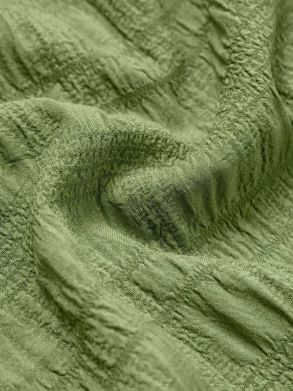 Close-up of textured green fabric showcasing the soft, breathable material perfect for summer dresses.