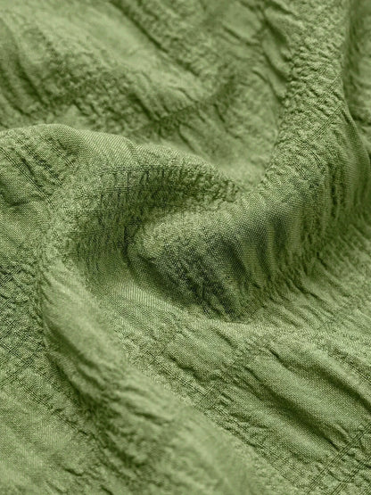 Close-up of textured green fabric showcasing the soft, breathable material perfect for summer dresses.