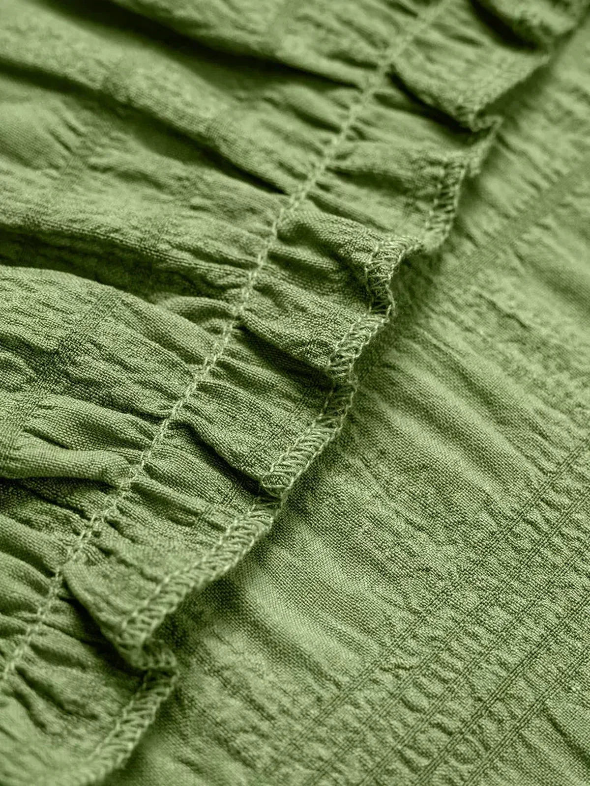 Close-up of the textured ruffled fabric in a soft olive green, perfect for summer dresses and casual wear.