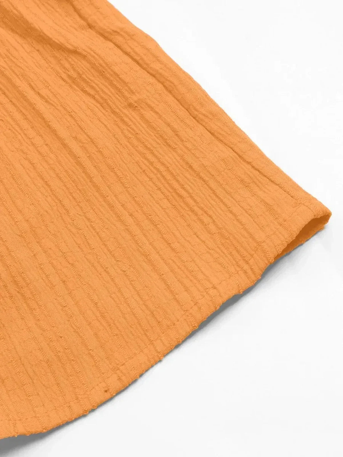 Close-up of the textured hem of an orange dress, showcasing its soft fabric and playful style for summer wear.