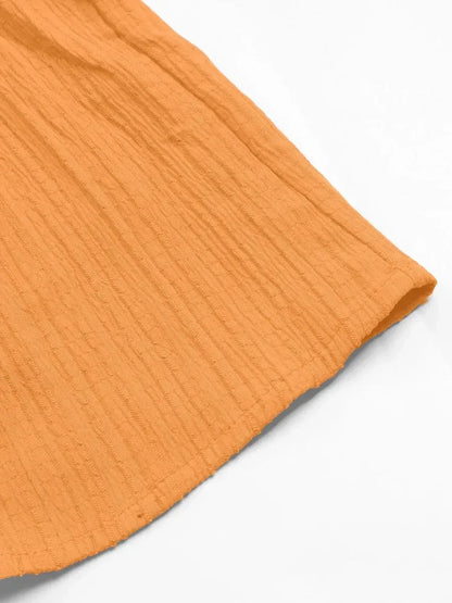 Close-up of the textured hem of an orange dress, showcasing its soft fabric and playful style for summer wear.