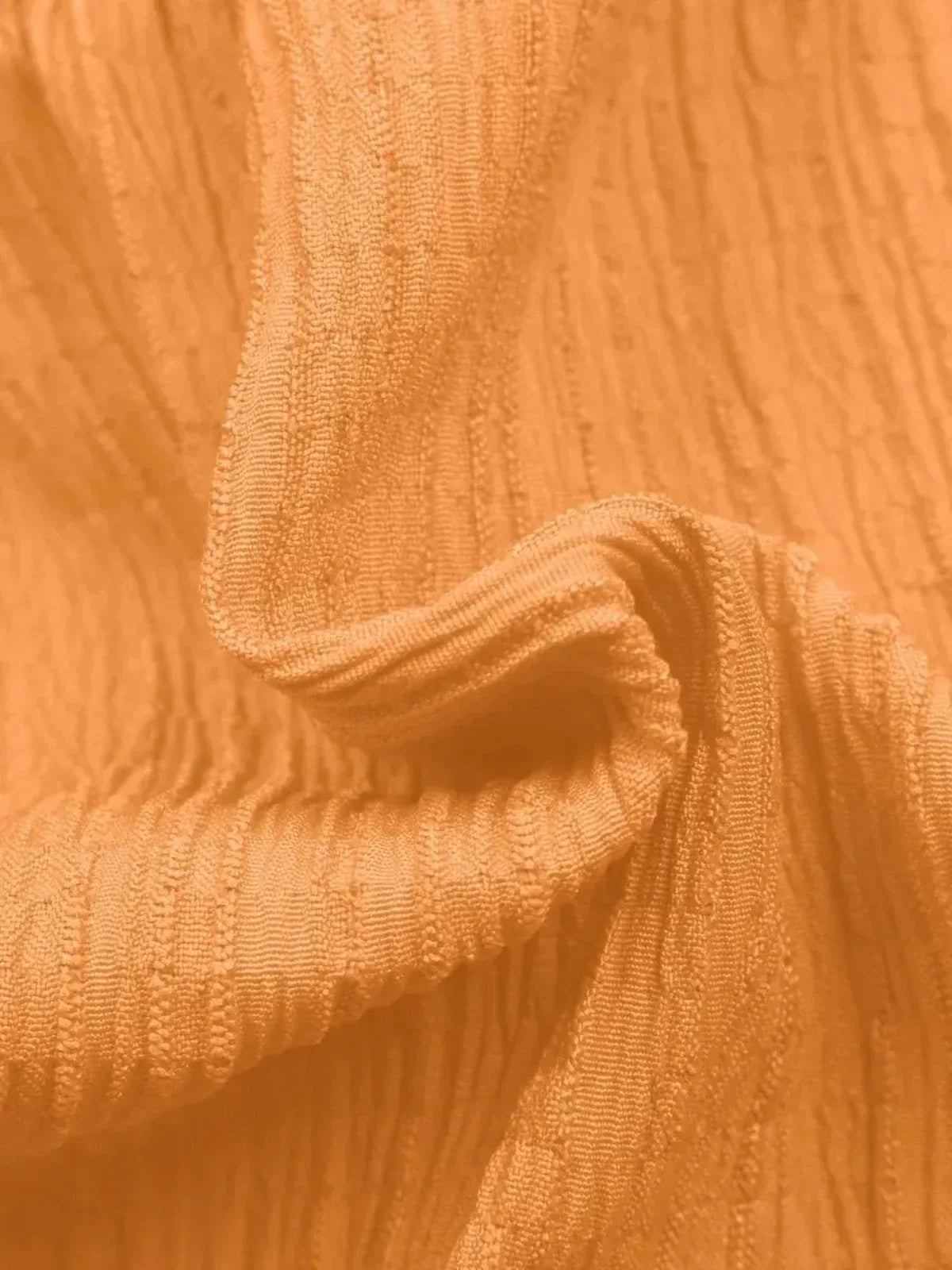 Textured orange fabric showcasing a soft, elegant drape perfect for summer dresses and casual wear.