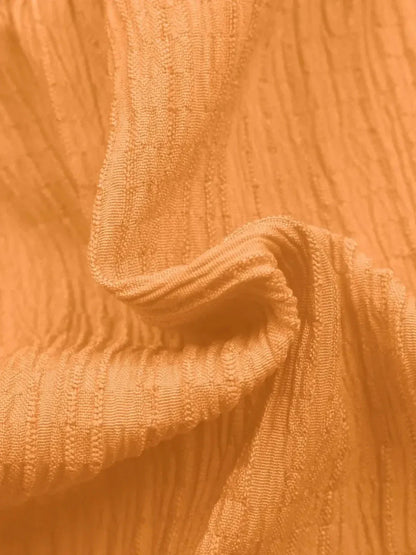 Textured orange fabric showcasing a soft, elegant drape perfect for summer dresses and casual wear.