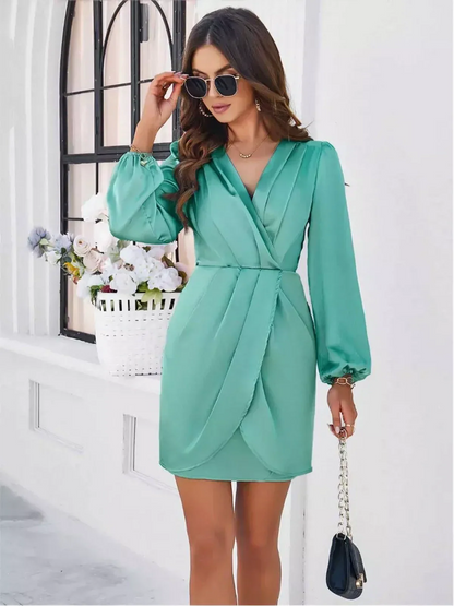 Model wearing an elegant green Orchid Wrap Mini Dress with long sleeves, V-neckline, and tulip hem, perfect for summer events.