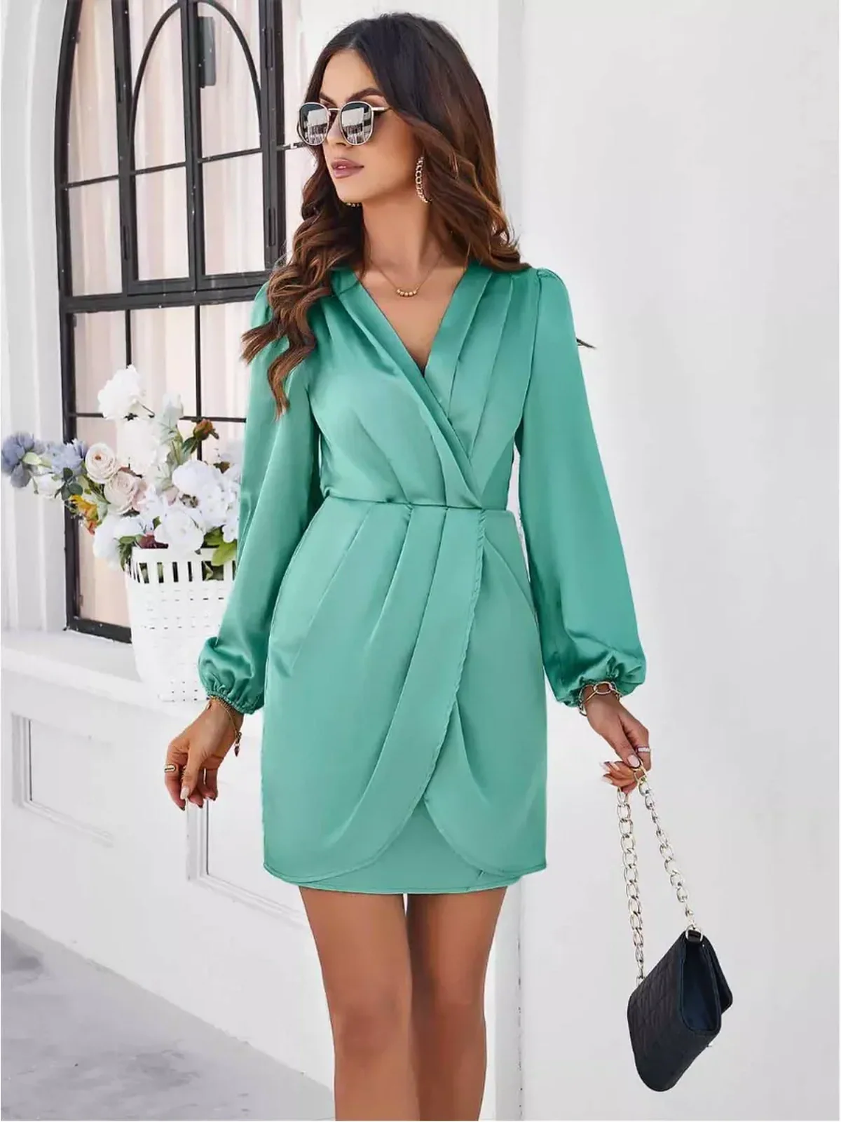 Model wearing a green Orchid Wrap Mini Dress with long sleeves, V-neck, and a stylish tulip hem, ideal for summer events.