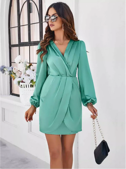 Model wearing a green Orchid Wrap Mini Dress with long sleeves, V-neck, and a stylish tulip hem, ideal for summer events.