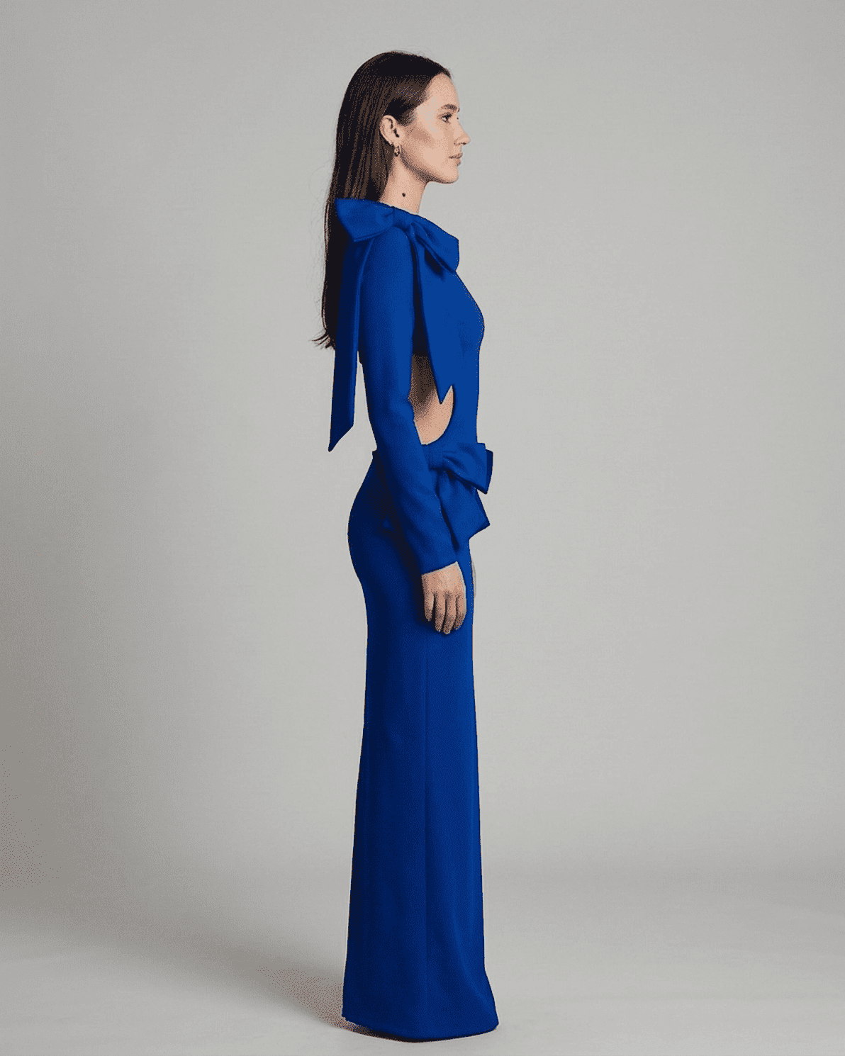 Orion Maxi Dress by Slimona featuring a long sleeve bodycon silhouette with a cut-out waist and sculptural bows in blue.