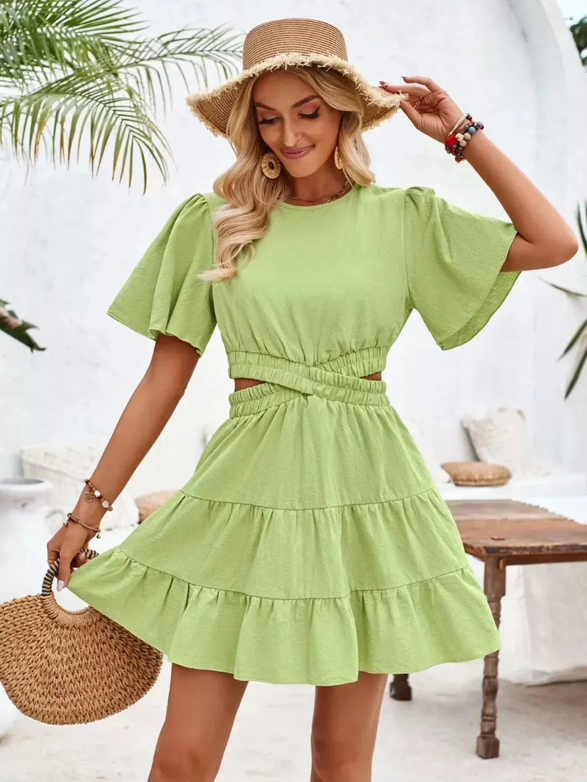 Model in a chic green Palm Bloom Mini Dress with flutter sleeves and tiered skirt, perfect for summer occasions.