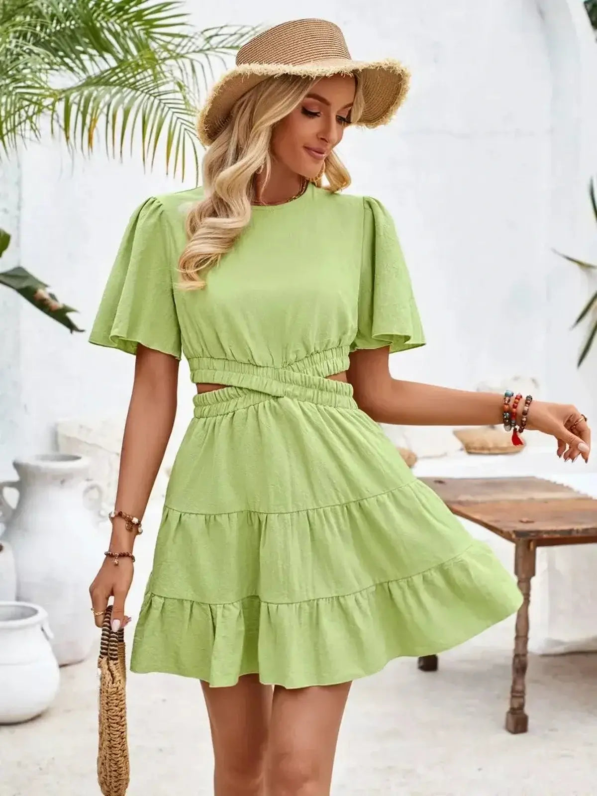 Stylish woman in a trendy green mini dress with flutter sleeves and tiered ruffle skirt, perfect for summer outings.