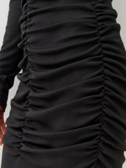 Close-up of the gathered ruching detail on a black mini dress, emphasizing its sleek silhouette and elegant style.