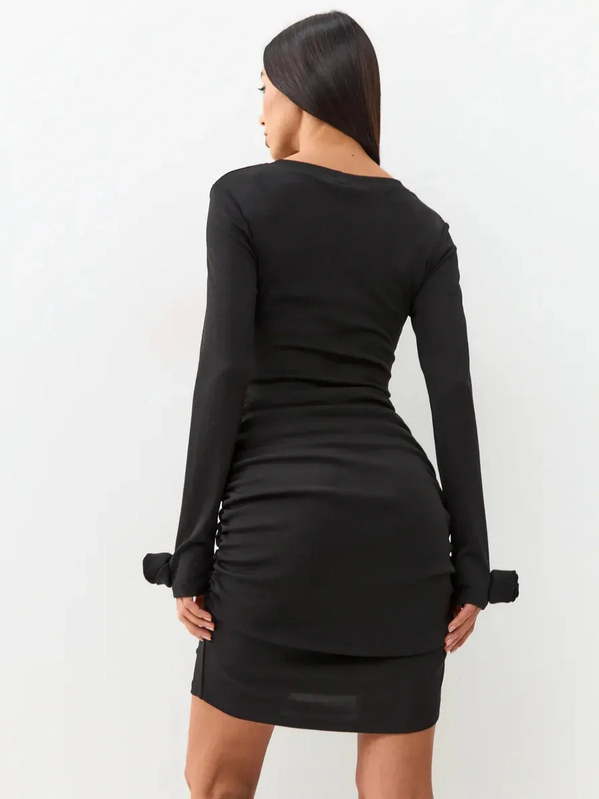 Back view of a black long sleeve mini dress with gathered ruching, perfect for evening elegance.