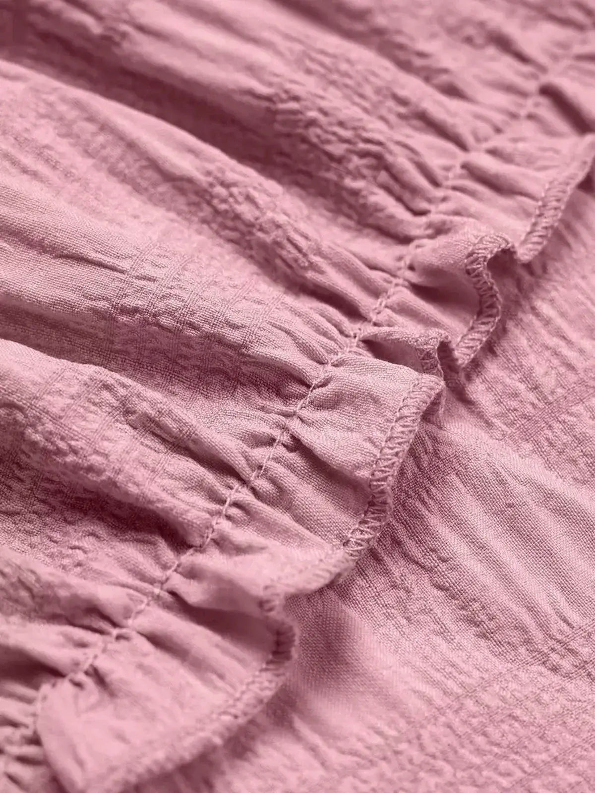 Close-up of the pink fabric showcasing soft ruching detail, perfect for summer dresses and elegant styling.
