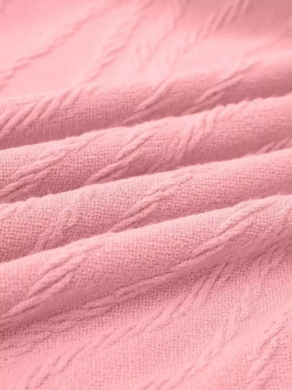 Close-up of soft pink textured fabric showcasing intricate knit details, ideal for stylish summer or casual dresses.