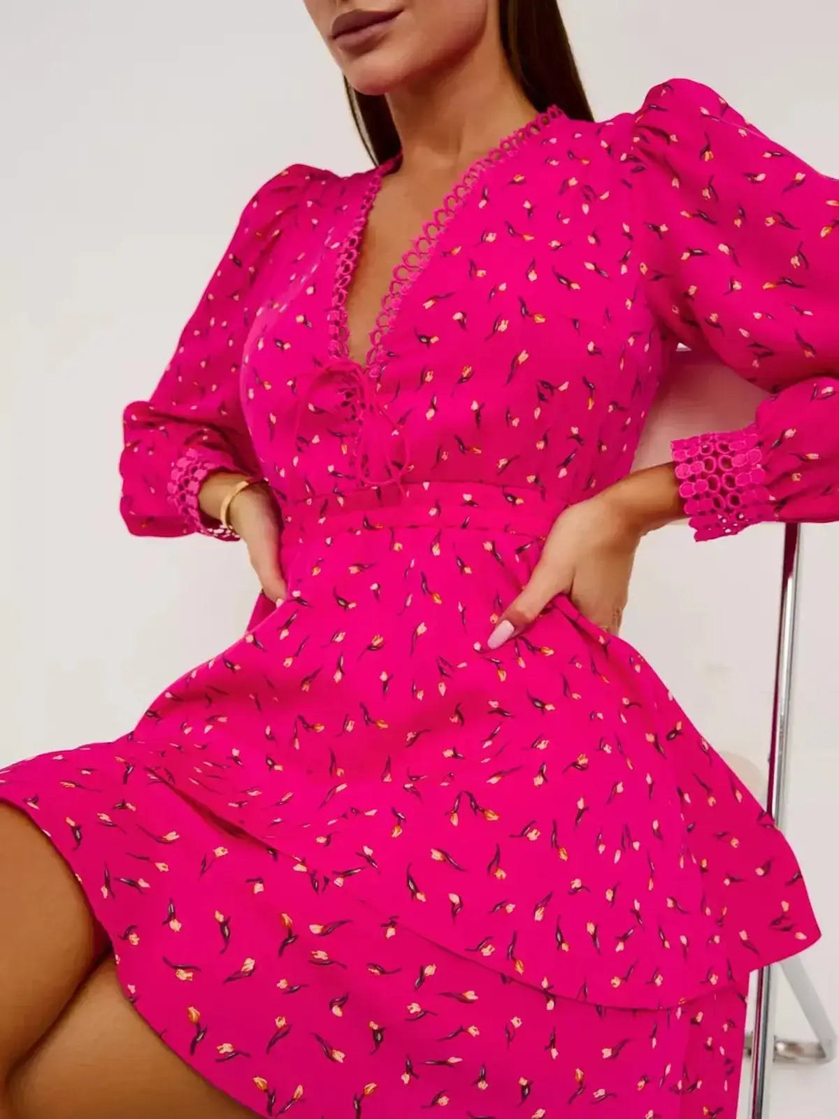 Model wearing Tulip Bloom pink dress with floral pattern, deep V-neckline, and flared skirt, perfect for summer events.