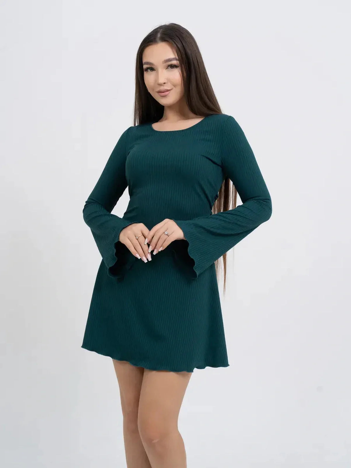 Woman wearing a long sleeve mini dress with flared sleeves in emerald green, showcasing a flattering ribbed design.