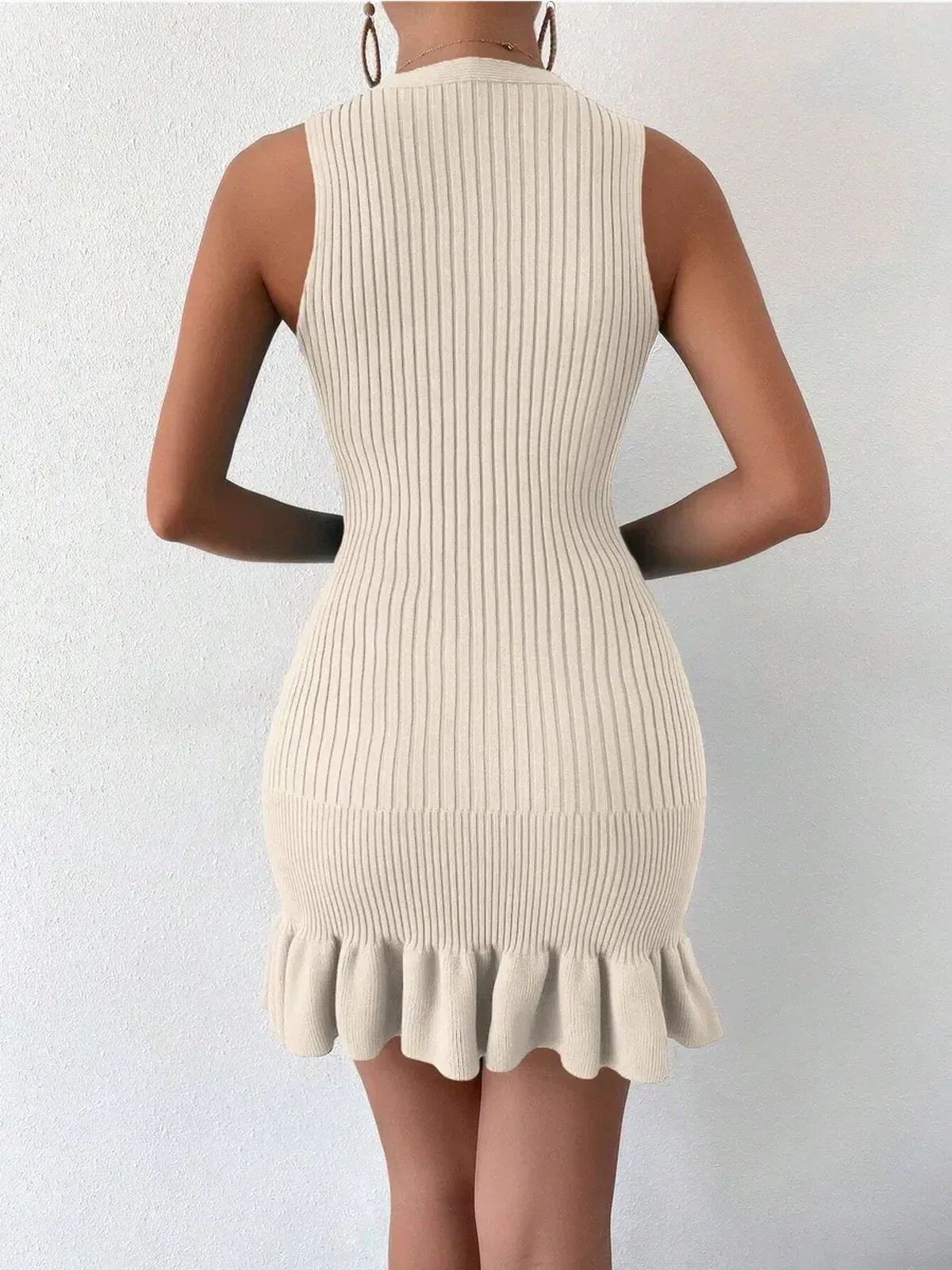 Back view of the Riviera Rib Mini Dress, featuring a fitted ribbed design and soft ruffled hem in a neutral color.