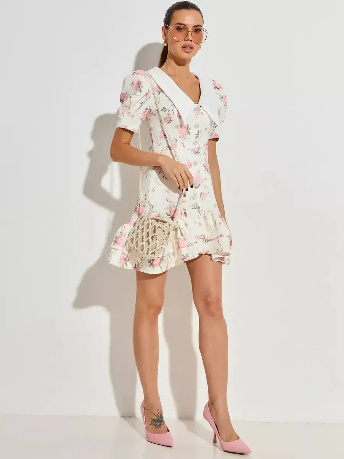 Model wearing a floral mini dress with puffed sleeves and flared hem, perfect for summer and weddings.