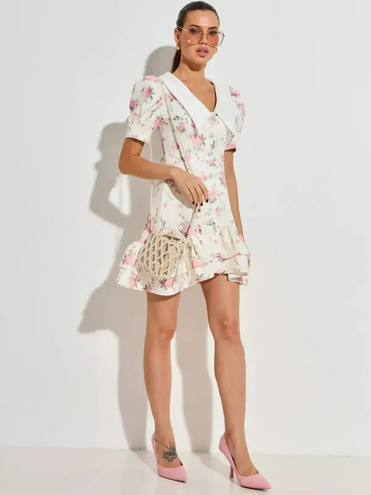 Model wearing a floral mini dress with puffed sleeves and flared hem, perfect for summer and weddings.