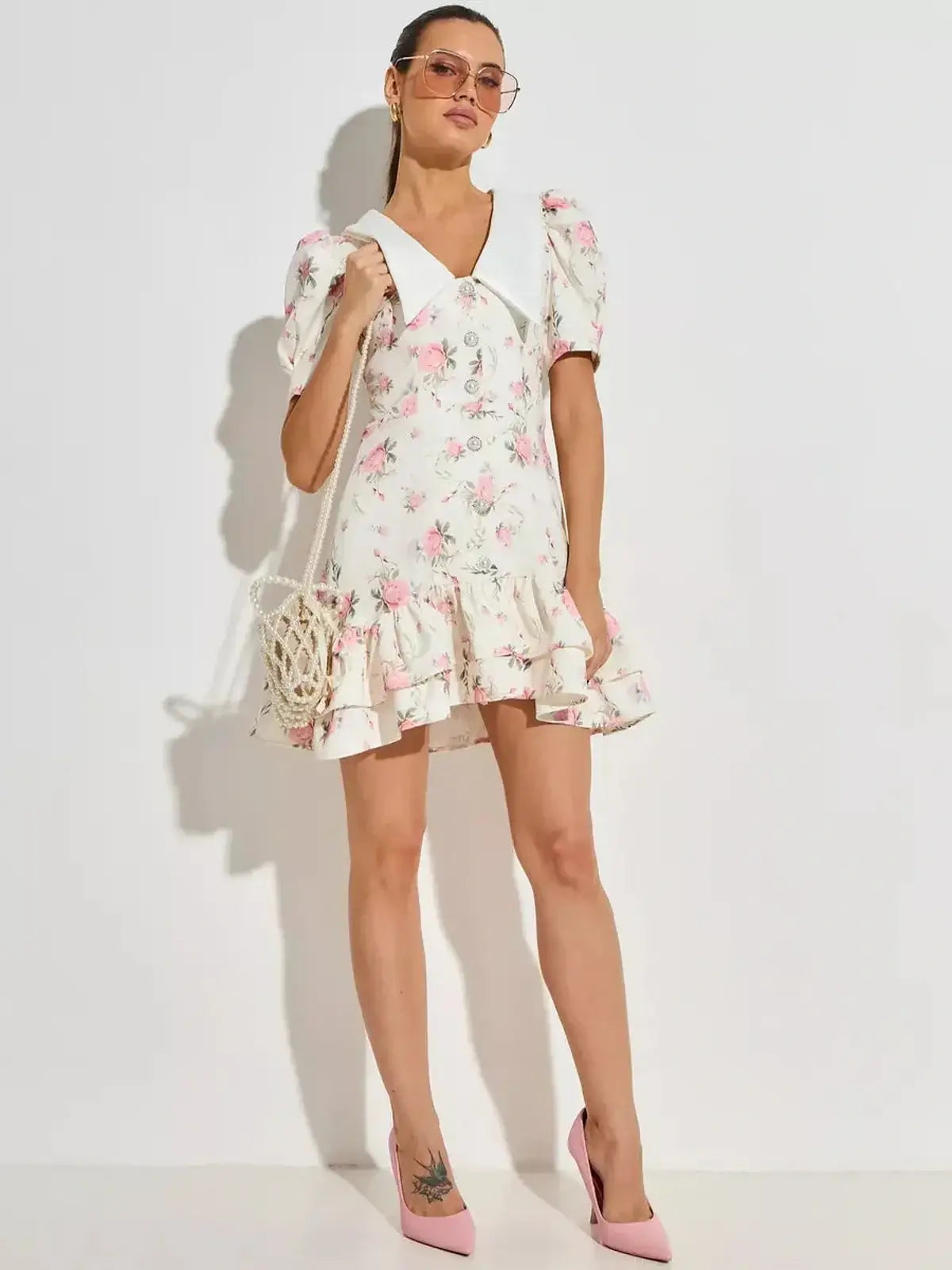White floral mini dress with pink prints, puffed sleeves, and flared hem, perfect for summer and wedding guest occasions.