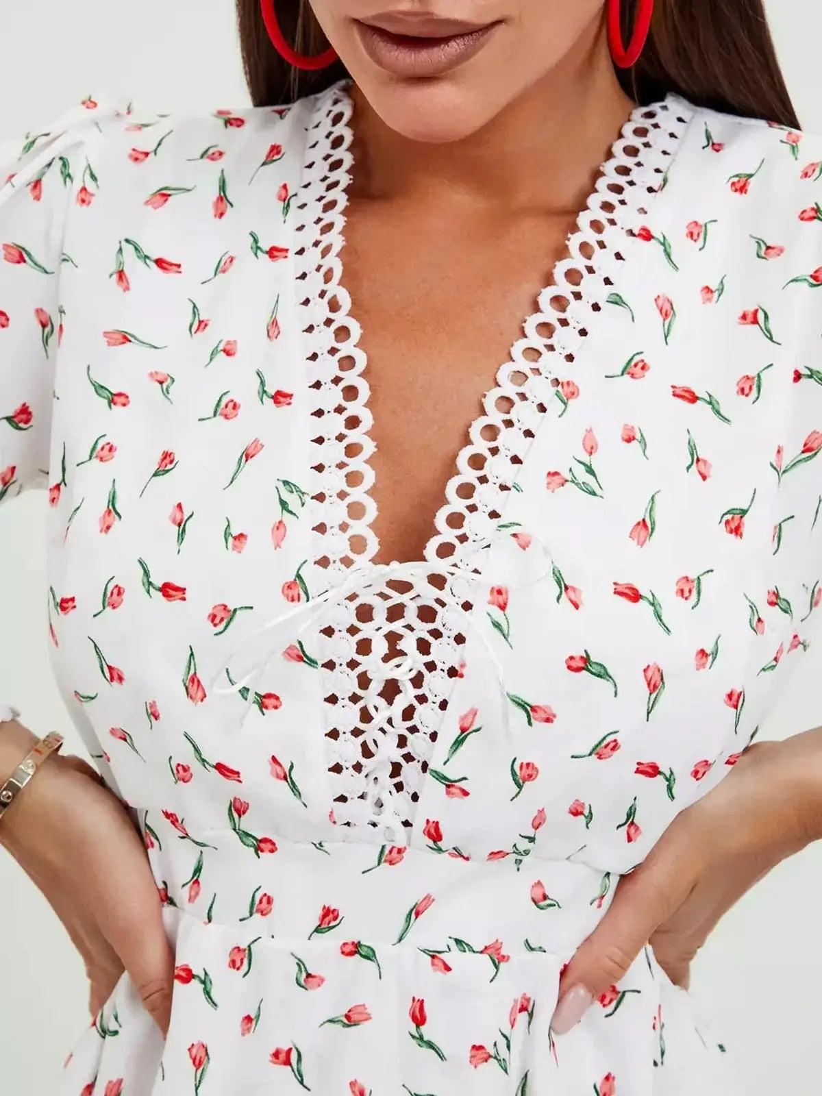 Close-up of a white dress with delicate rosebud print and lace detailing, perfect for summer occasions.