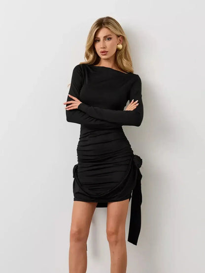 Sculpted black mini dress with long sleeves and side rosette detail for elegant evening wear.