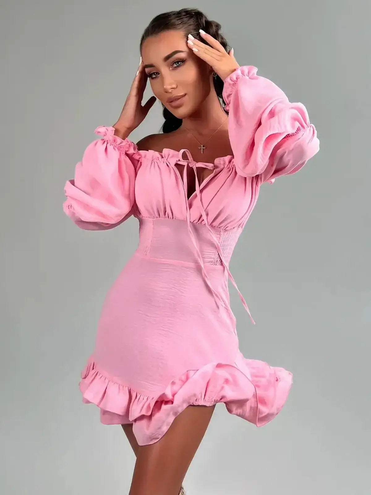 Model wearing a pink Ruffle Muse mini dress with off-shoulder design and long lantern sleeves.