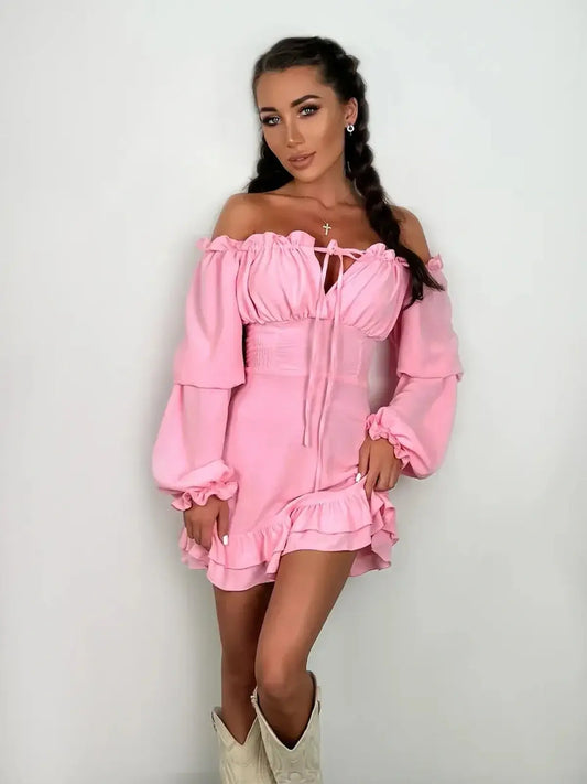Model wearing a pink off-shoulder mini dress with ruffled hemline and long sleeves, ideal for summer and party occasions.