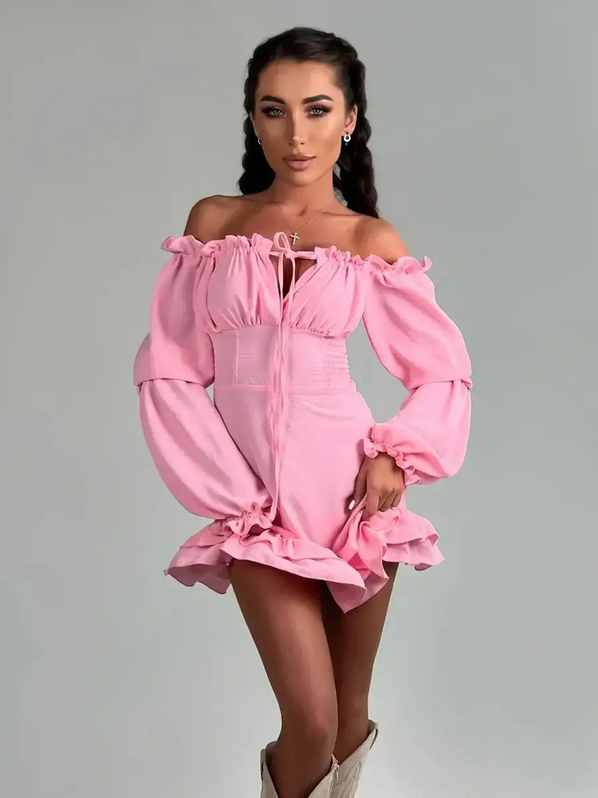 Model wearing a pink off-shoulder mini dress with flouncy hem and lantern sleeves, ideal for weddings and parties.