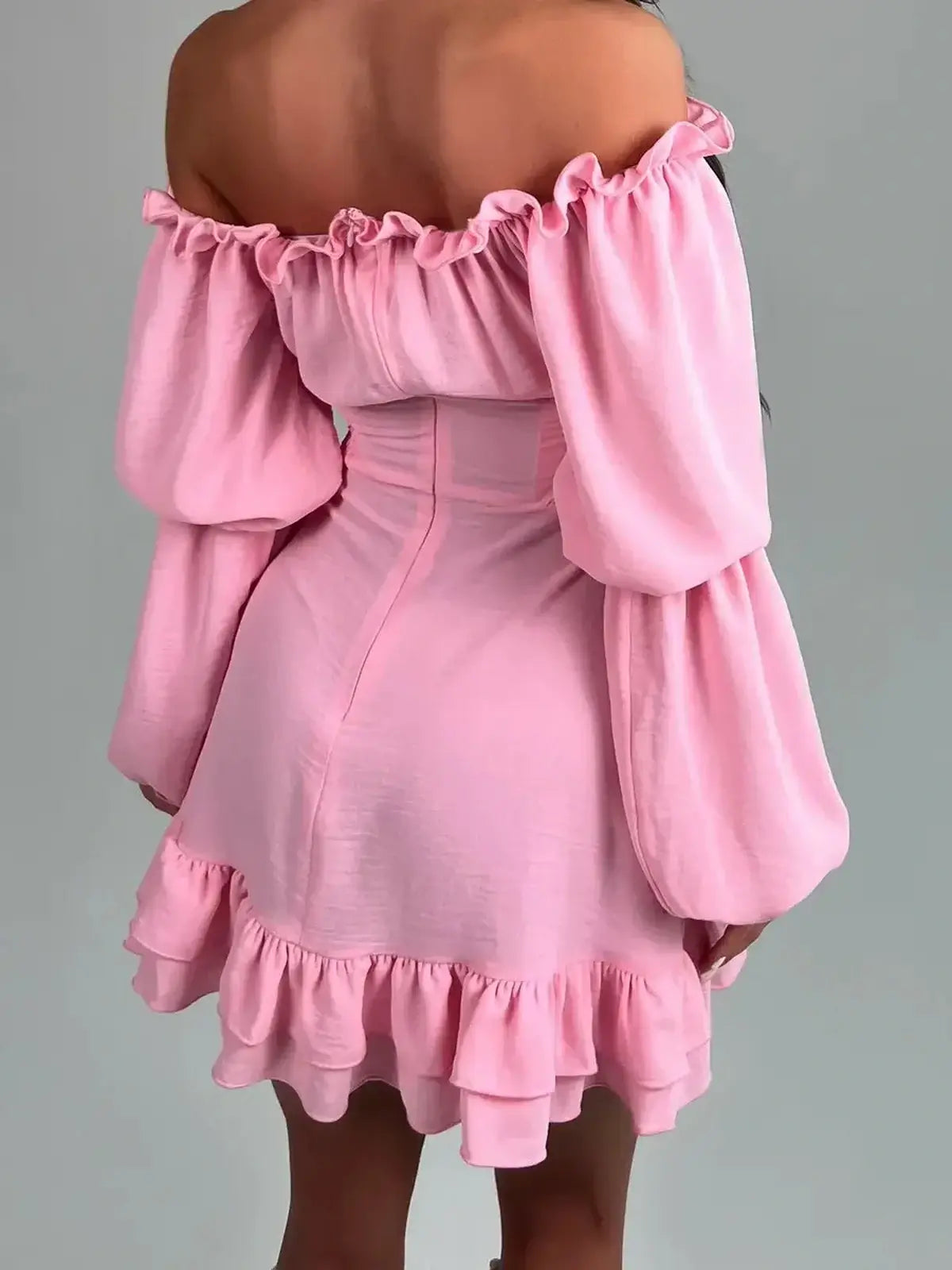 Back view of Ruffle Muse pink mini dress with off-shoulder design and flouncy hemline, ideal for summer and special occasions.