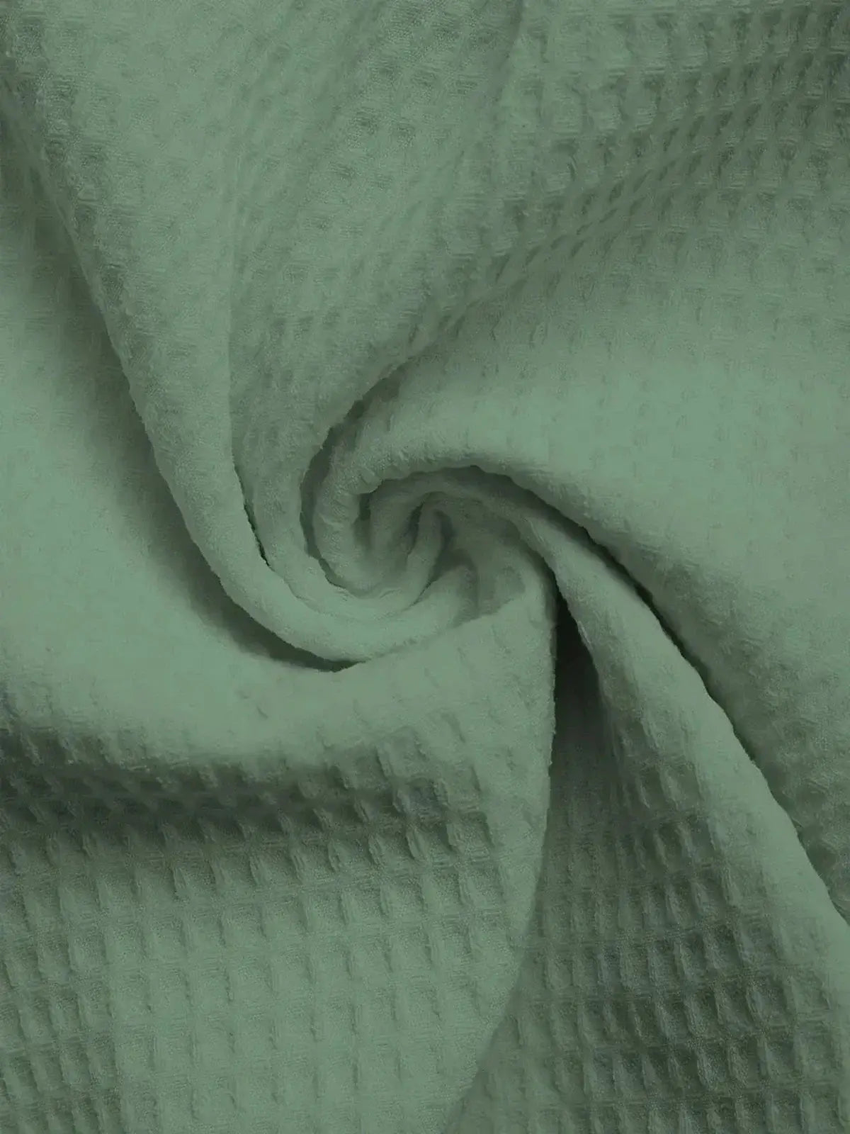 Soft textured sage green fabric showcasing a cozy waffle weave pattern, perfect for casual dresses or home decor.