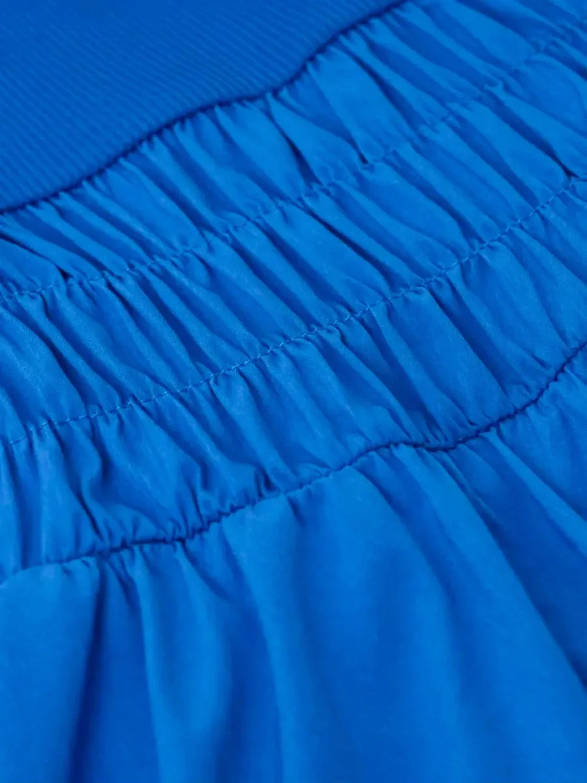 Close-up of the textured blue fabric and smocked detail of the Sapphire Tide Mini Dress, showcasing its stylish design.