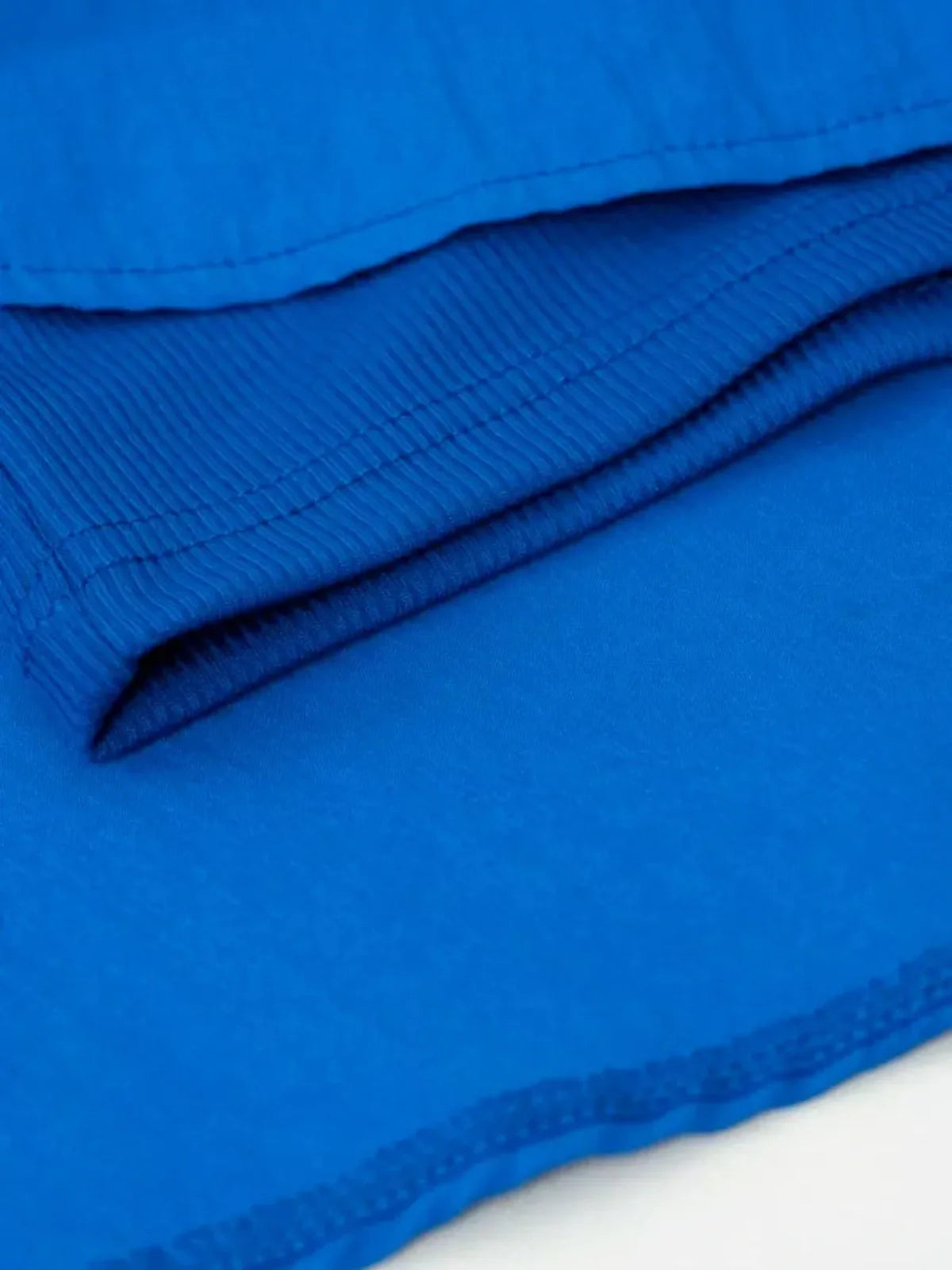 Close-up of rich blue fabric showcasing the ribbed and smooth textures of a mini dress.