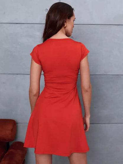 Back view of a woman in the scarlet Bloom Mini Dress, showcasing its feminine flared silhouette and cap sleeves.