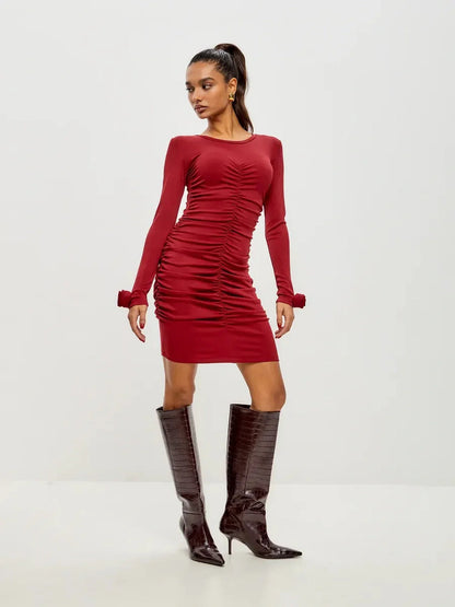 Model in a ruched red long sleeve dress with knee-high boots, perfect for cocktail parties or evening events.
