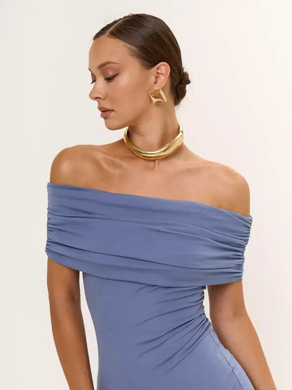 Woman wearing a blue off-shoulder bodycon dress with elegant draping and gold accessories, perfect for formal occasions.