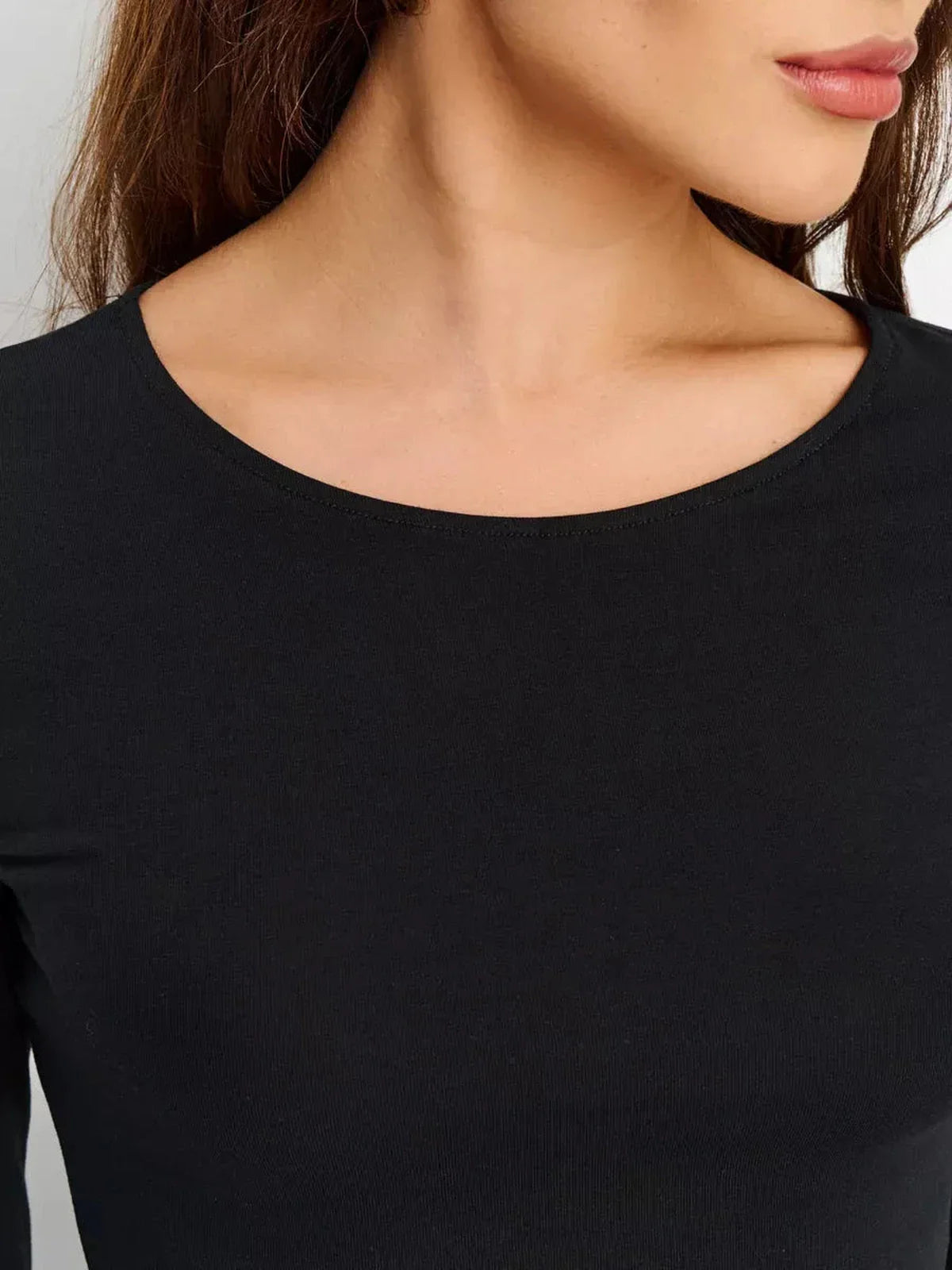 Close-up of the rounded neckline of a black Sculpted Hour Mini Dress, showcasing its sleek design and fit.