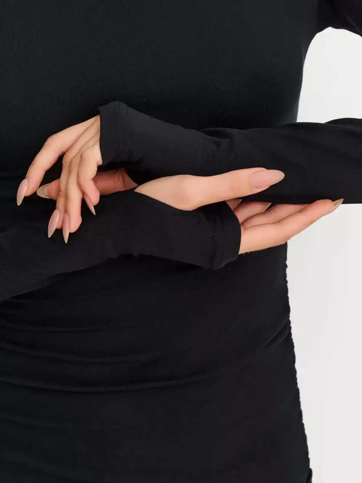 Close-up of hands in fitted long sleeves with thumbhole details, showcasing the modern design of the Sculpted Hour Mini Dress.
