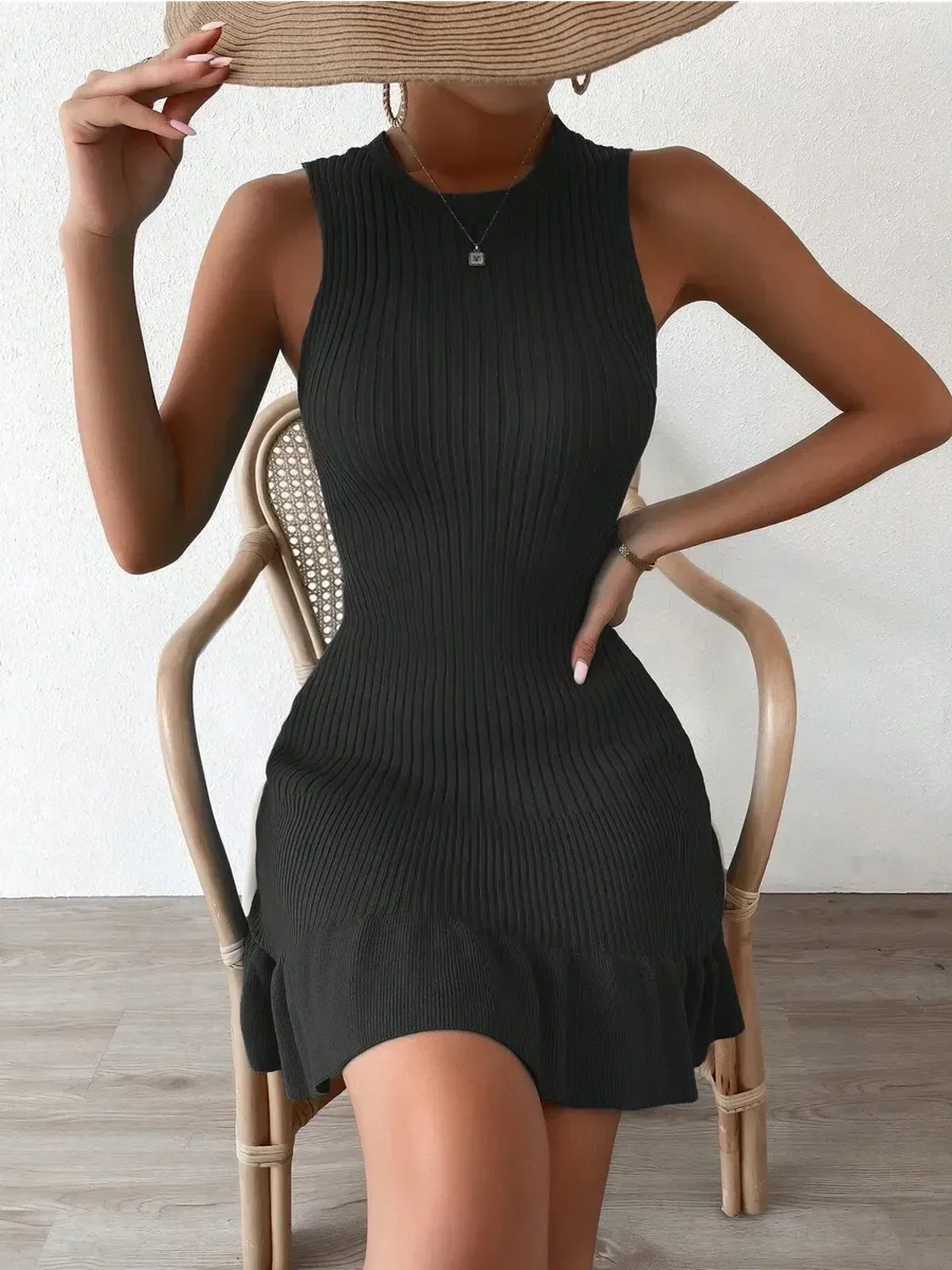 Stylish model in a sleeveless black mini dress, showcasing ribbed texture and a flattering silhouette.