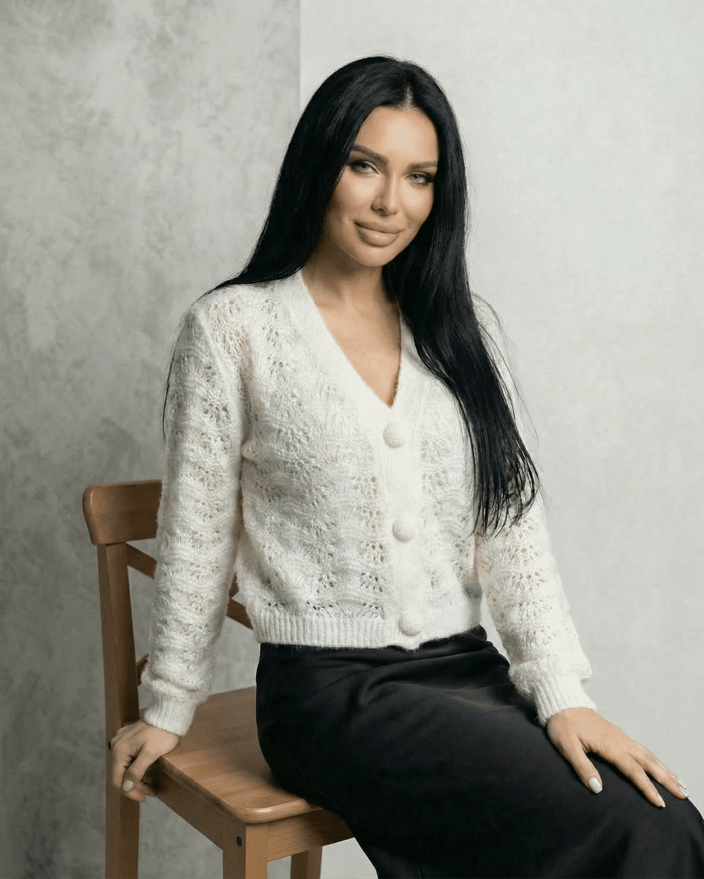 Serena Cardigan by Slimona featuring a lace knit texture and button front design on a model sitting elegantly.