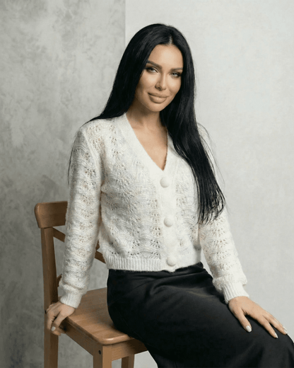 Serena Cardigan by Slimona featuring a lace knit texture and button front design on a model sitting elegantly.