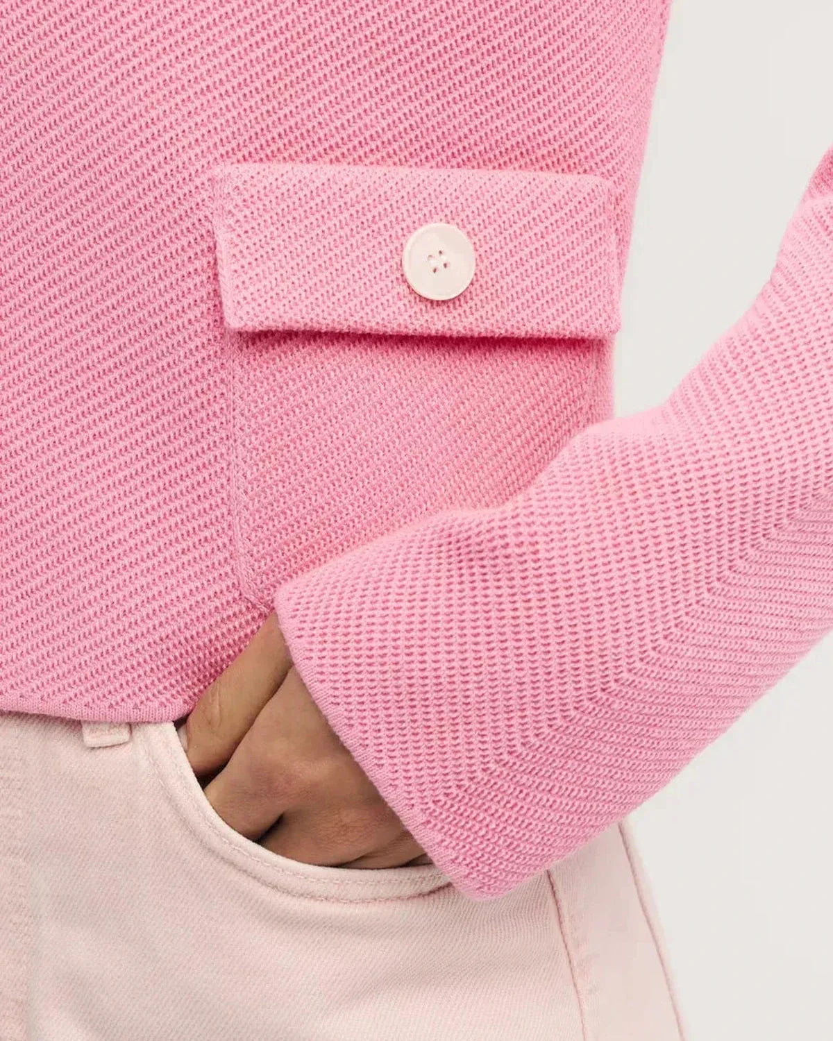 Detail of the Serena Jacket by Slimona, featuring a pink button closure and textured fabric finish.