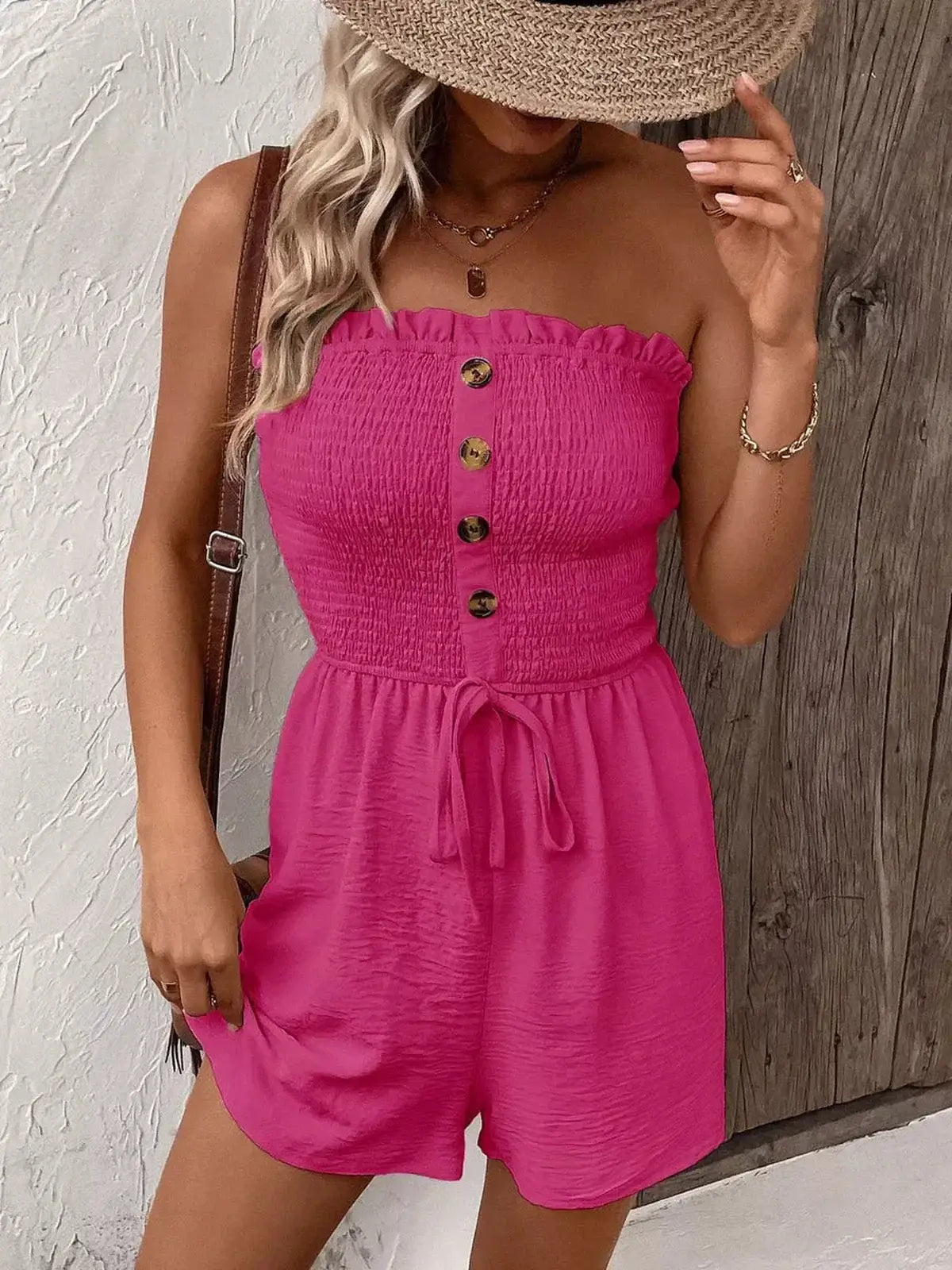 Model wearing a pink strapless mini dress with buttons and a self-tie waist, perfect for summer adventures.